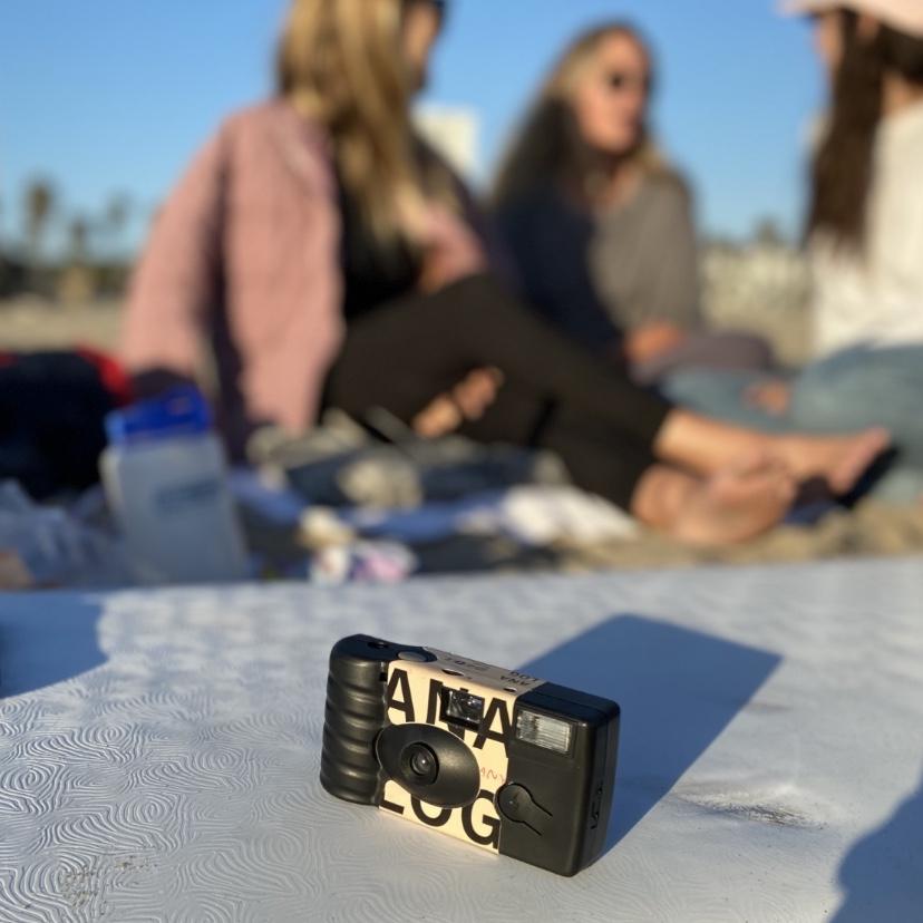 Tan Disposable Camera at Beach on Surfboard